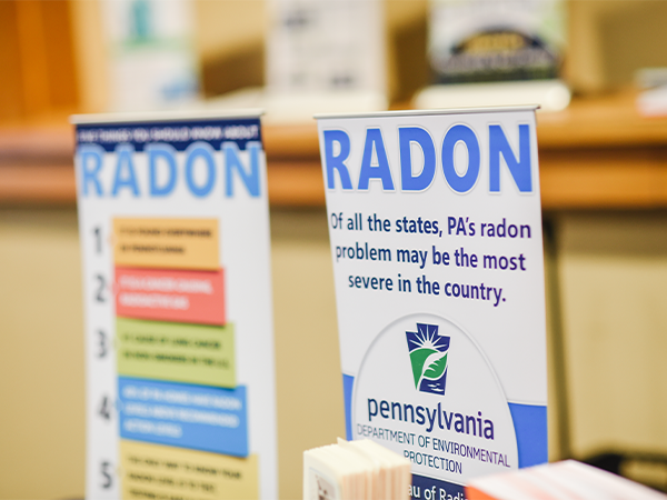 Two signs, explaining the potential dangers of radon, are displayed during a public health community event.